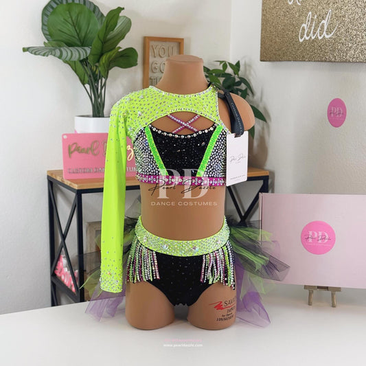 Neon lime and black rhinestone dance costume with one sleeve, pink and green accents, rhinestone fringe waistband, and layered green black and purple tulle bustle skirt by Pearl Dazzle.