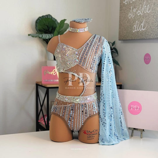 Icy blue one-shoulder contemporary costume with rhinestones, nude illusion mesh, high-waisted bottoms, and detachable sheer sleeve.
